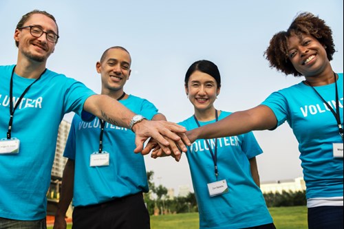 Group of volunteers linking hands outdoors